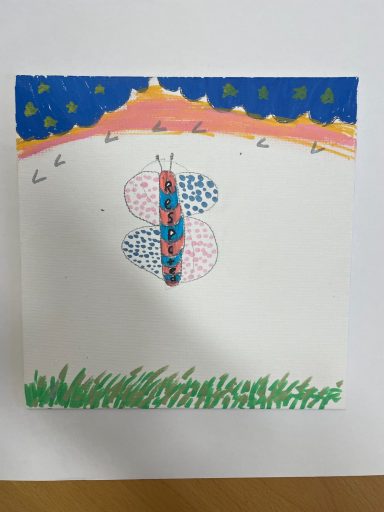 Colourful butterfly drawing with a blue sky, orange sunset, and green grass.